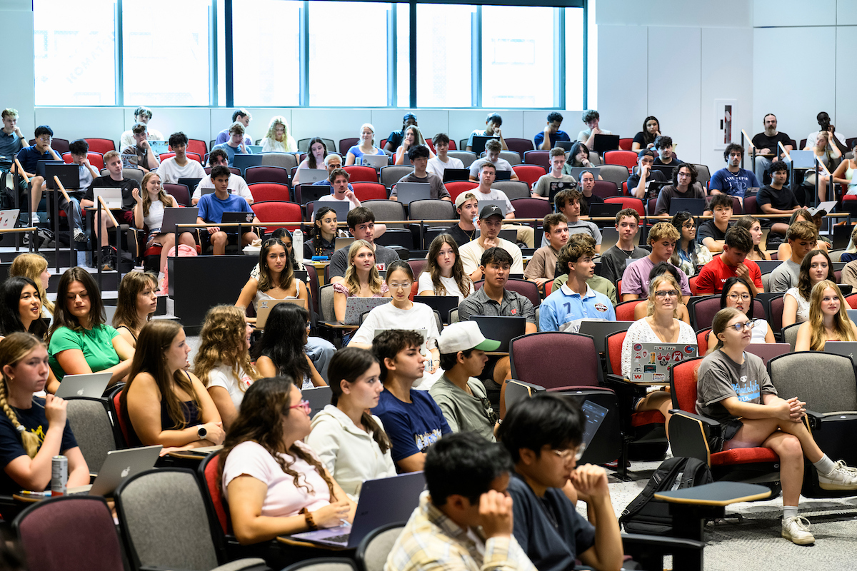 Students in a large lecture hall listen to a presenter
